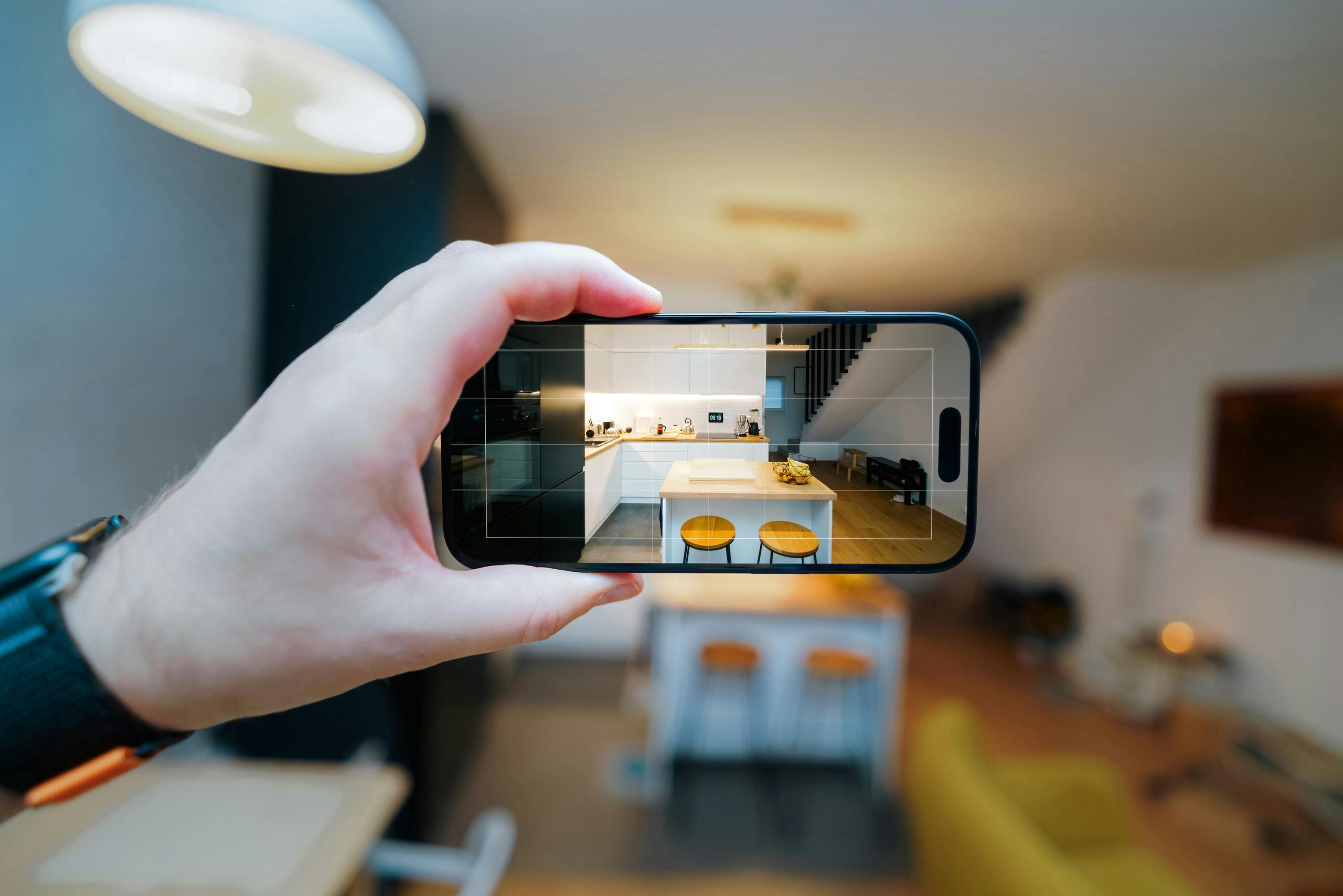 Person holding up smartphone to capture virtual tour of modern room
