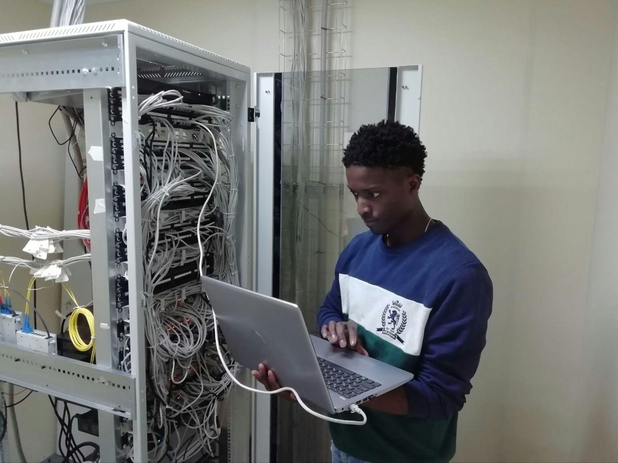 Professional setting up network infrastructure with laptop and server rack
