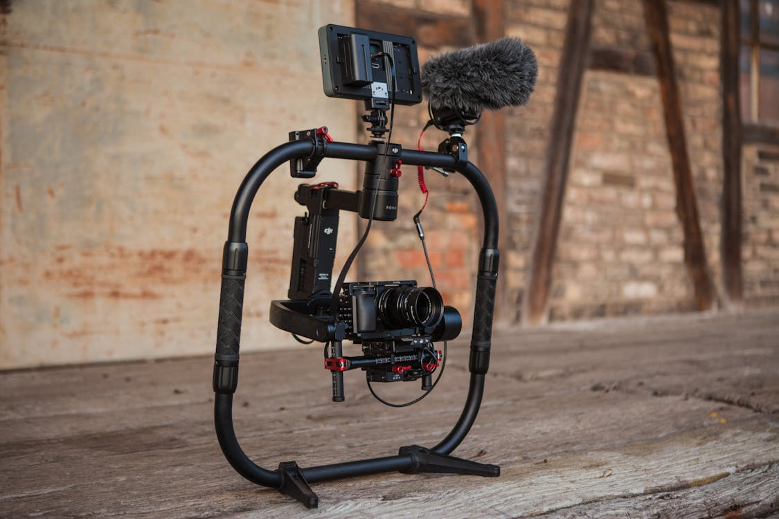 A high-end camera rig with an attached microphone sits on a wooden floor